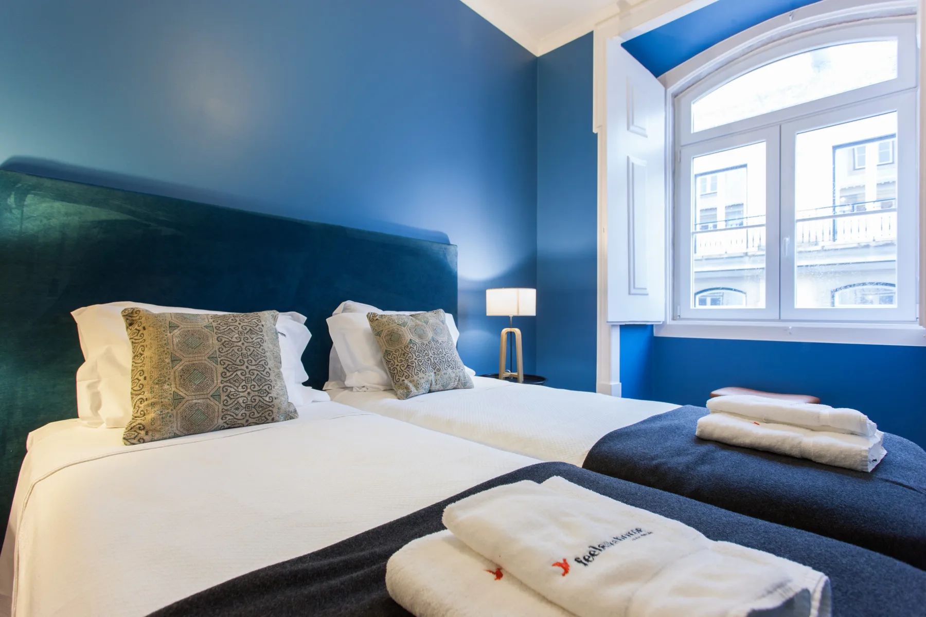 Un dormitorio con una cama bien hecha y una ventana grande.