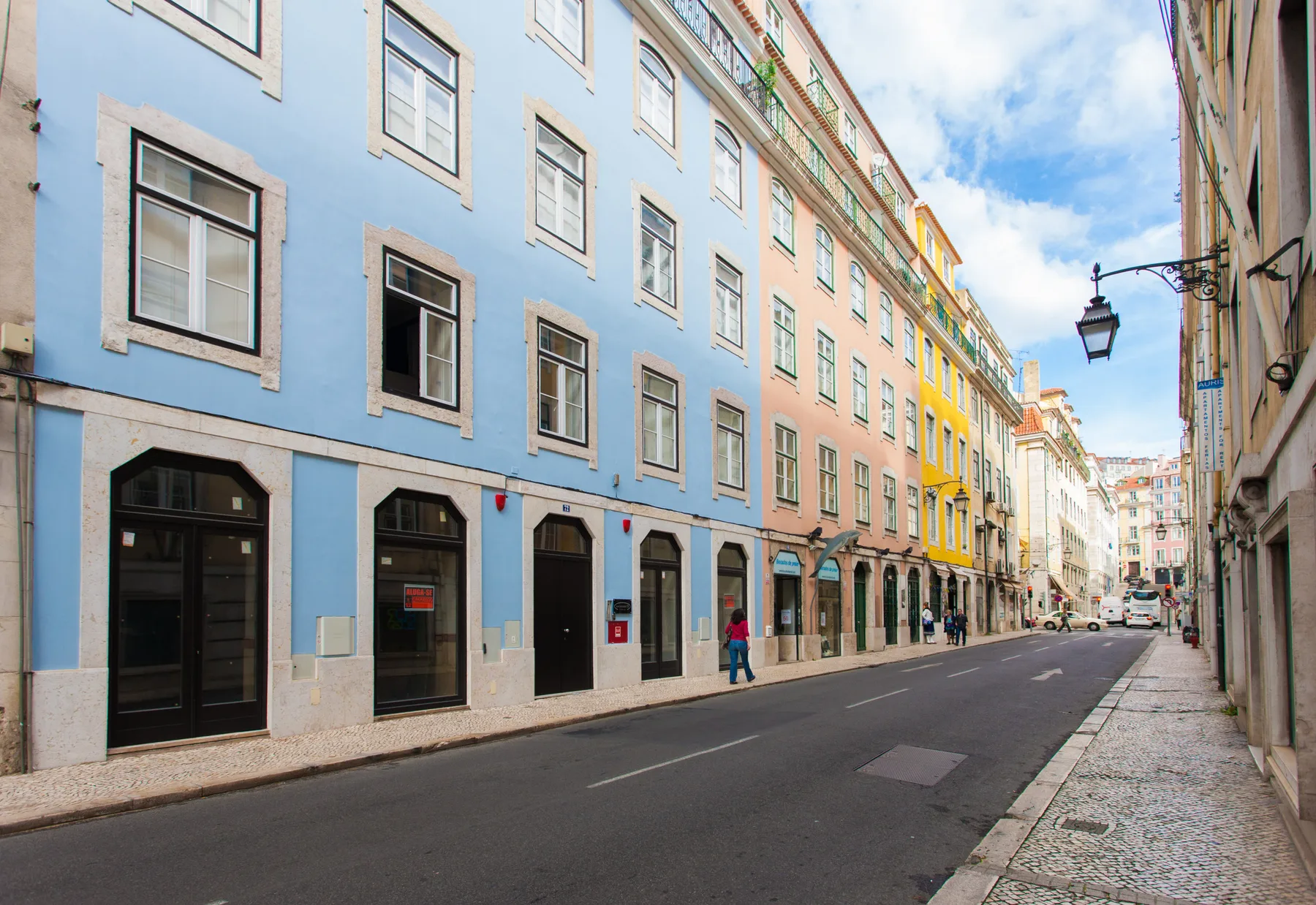 Una calle urbana bordeada de edificios coloridos de varias plantas y tiendas.