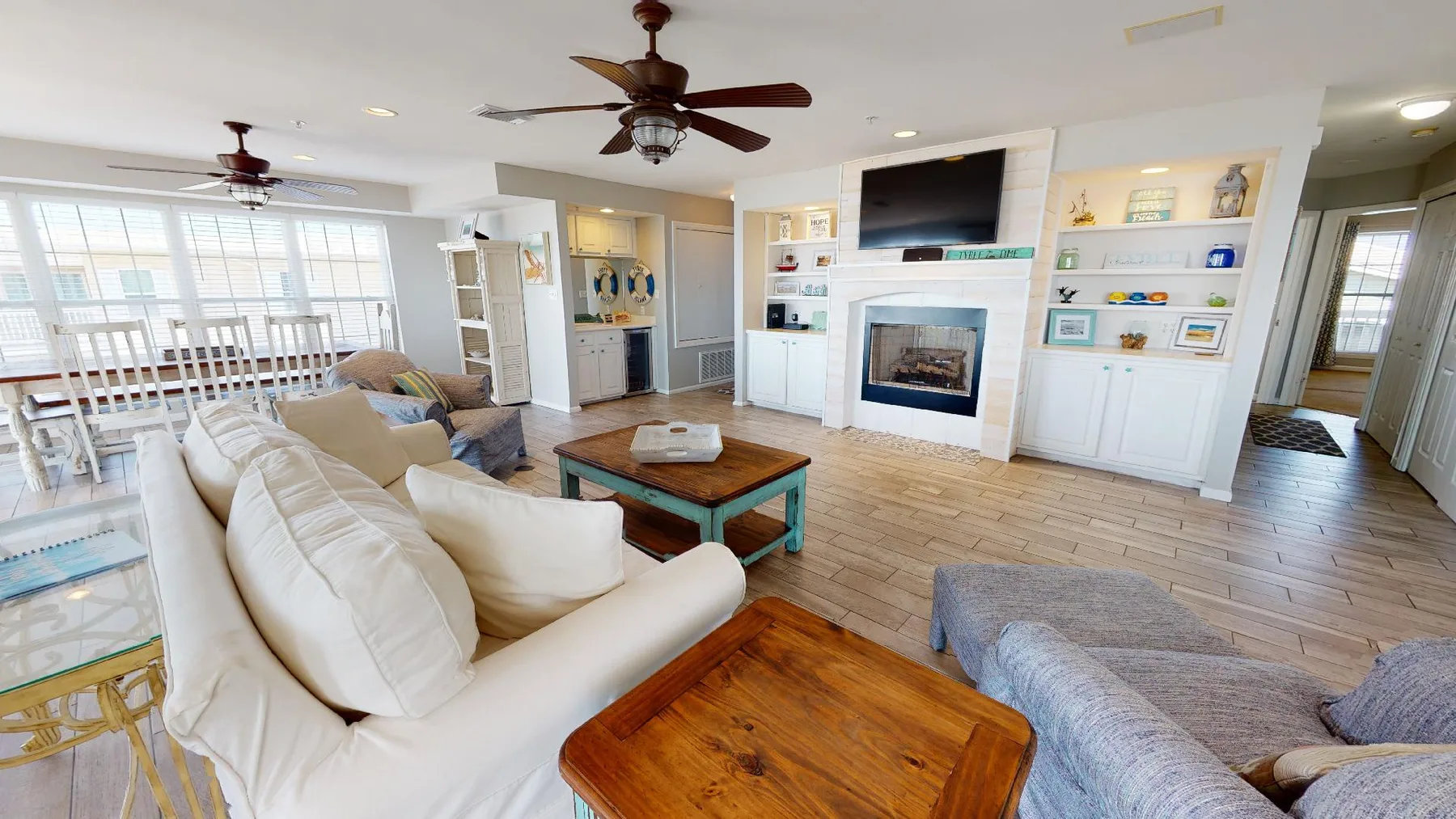 A bright living room with seating, a wooden coffee table, and a fireplace.