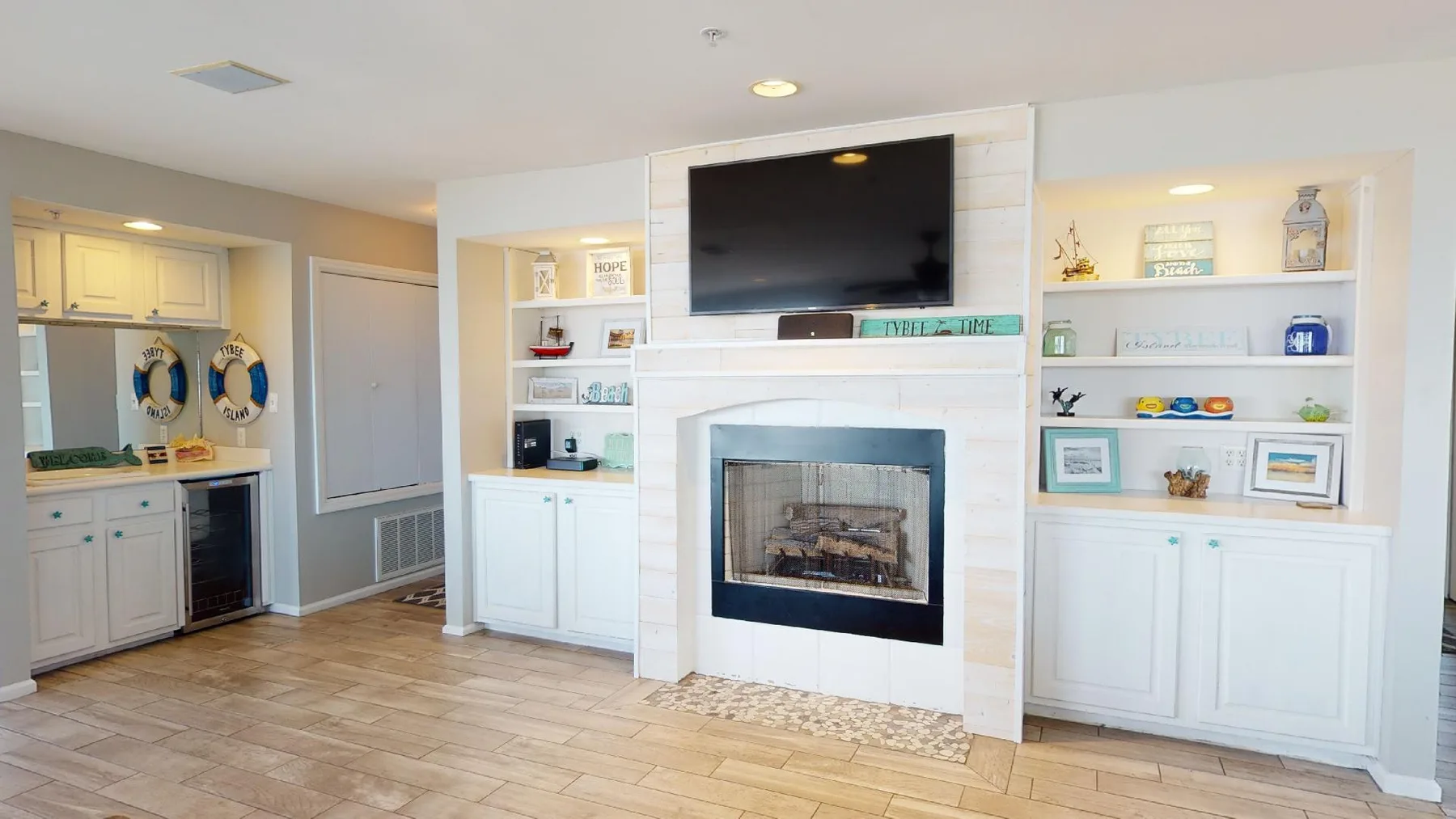 Sala de estar con chimenea y televisor integrados en estanterías blancas.