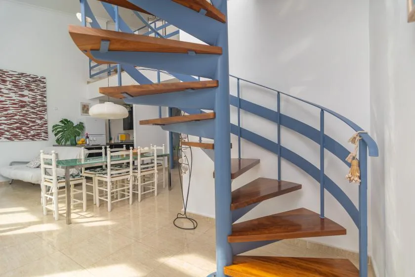 An open staircase with wooden steps stands beside a dining area.