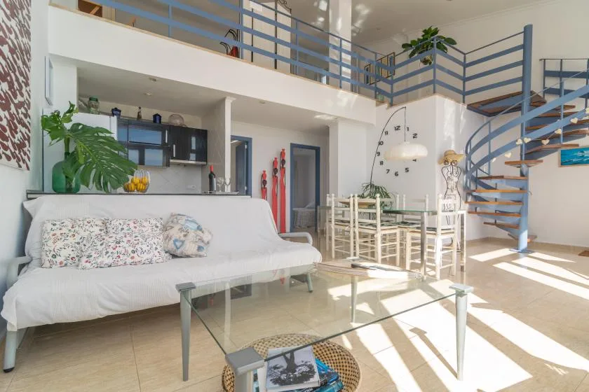 A bright open-plan living and dining area with a staircase and mezzanine.