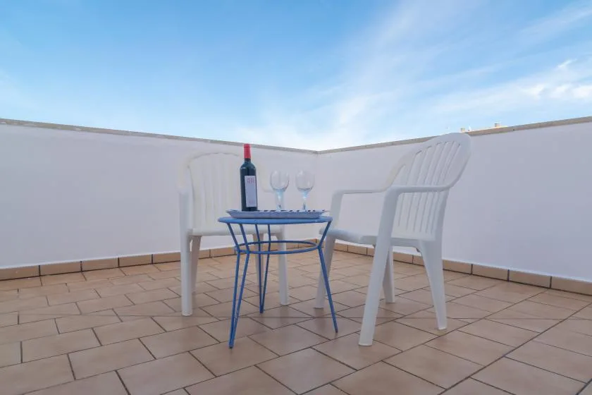 A small outdoor seating area with a table, chairs, and drinks on a tiled terrace.