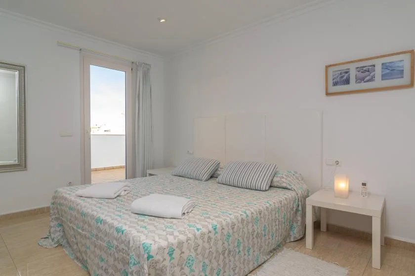 A bright bedroom with a patterned bed beside a window.