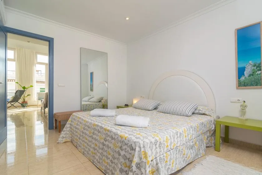 A bright bedroom with a double bed and a blue-trimmed doorway.