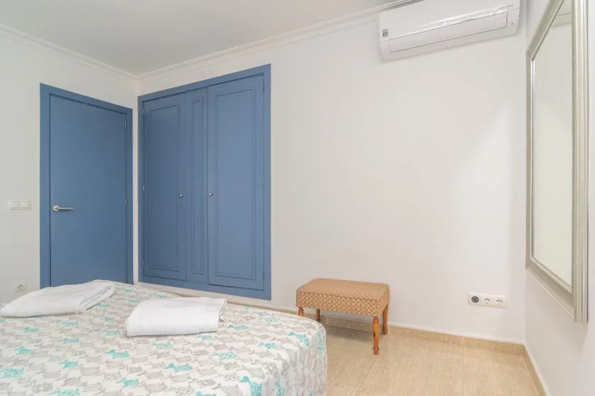 A bedroom with a patterned bedspread, blue doors, and a small bench.