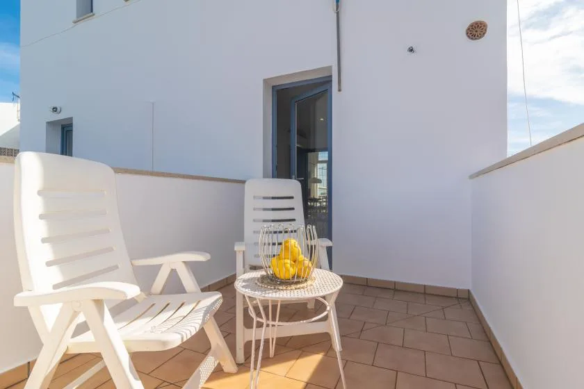 A small outdoor terrace has white seating and a round table.