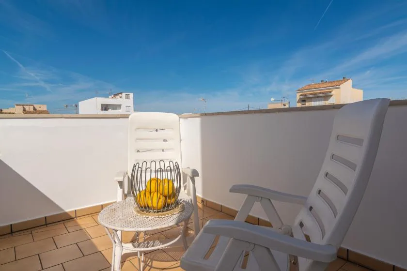 A sunlit rooftop terrace has outdoor seating and a small round table.