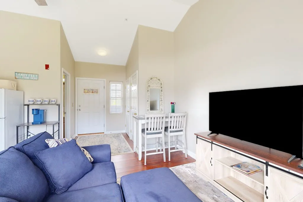 A bright living room with blue seating and a large television.