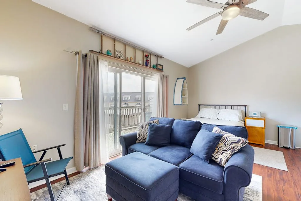A living room with blue seating beside a bright sliding glass door.