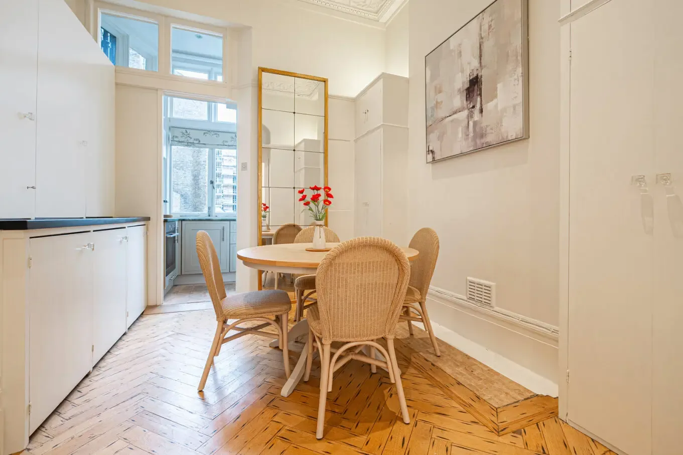A bright dining area with a wooden table and chairs beside tall windows.