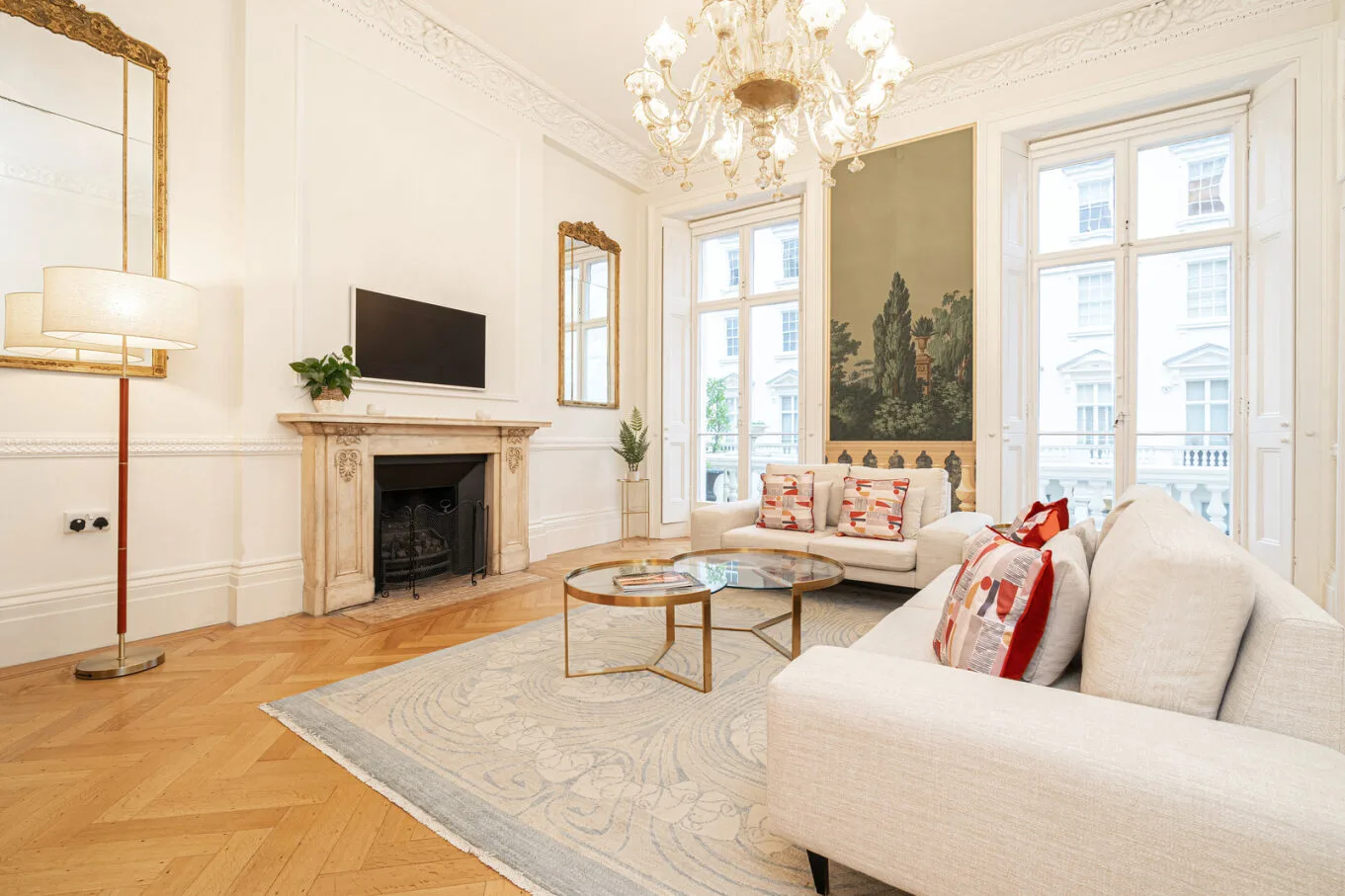 A bright living room with light seating, a fireplace, and tall windows.