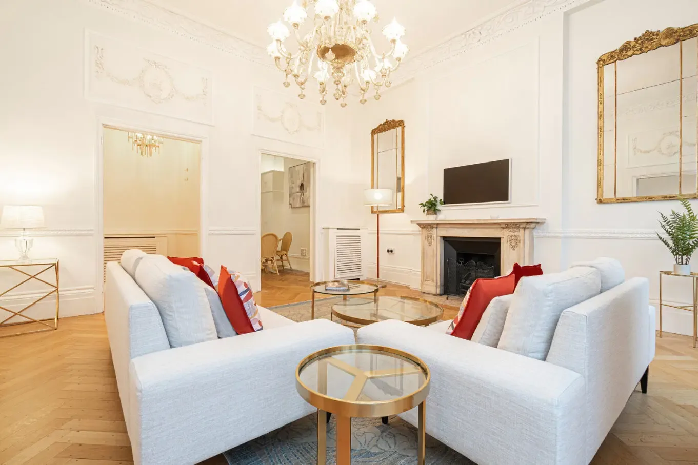 An elegant living room with pale seating arranged around a glass coffee table.