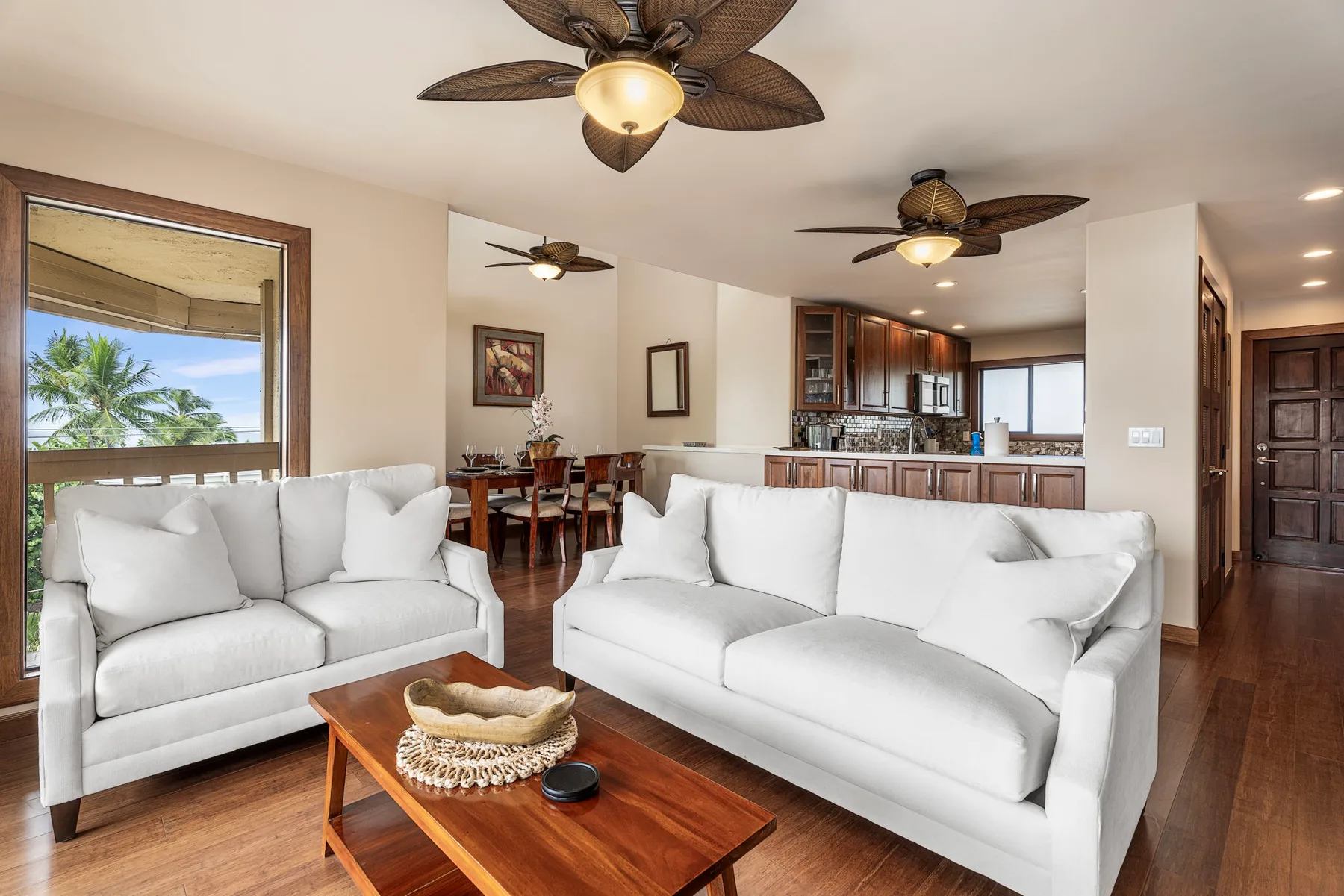 An open-plan living and dining area with white seating and a kitchen beyond.