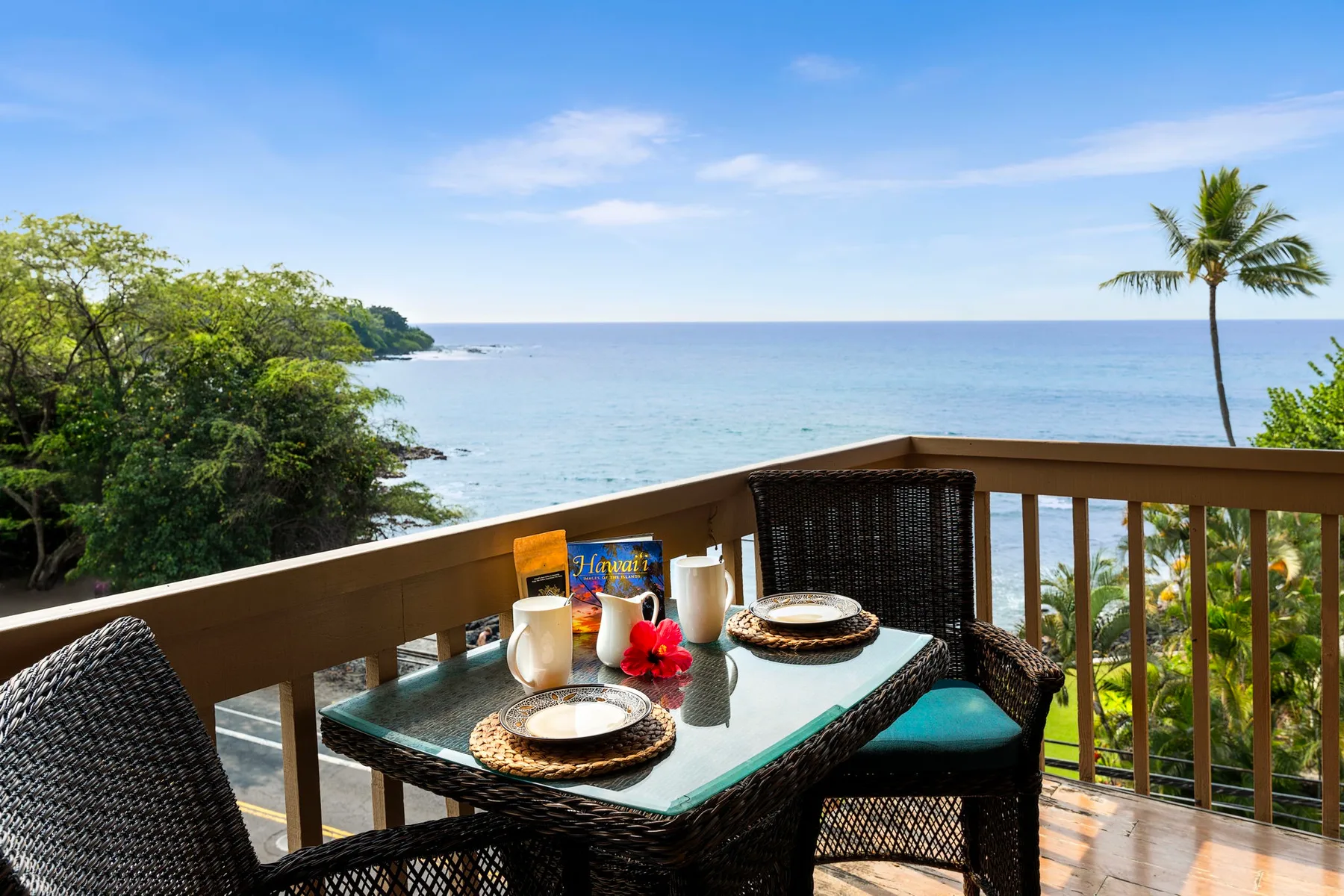 A balcony dining area overlooks the ocean, with a table and outdoor seating.