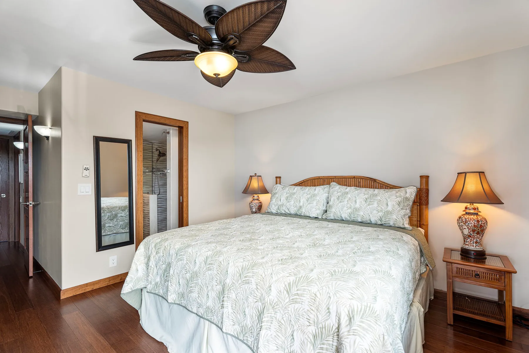 A bedroom with a bed, matching bedside tables, and a ceiling fan.