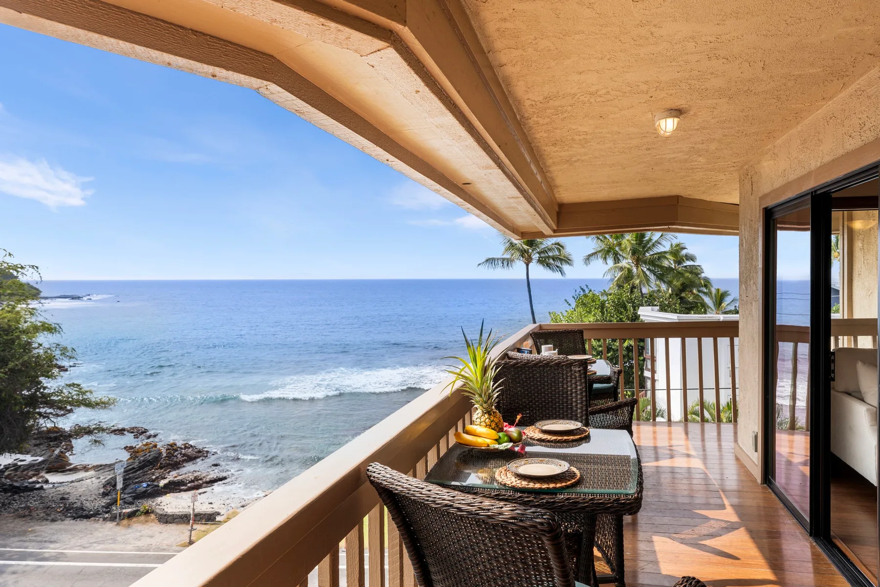 A balcony dining area overlooks the ocean, with a table and chairs.