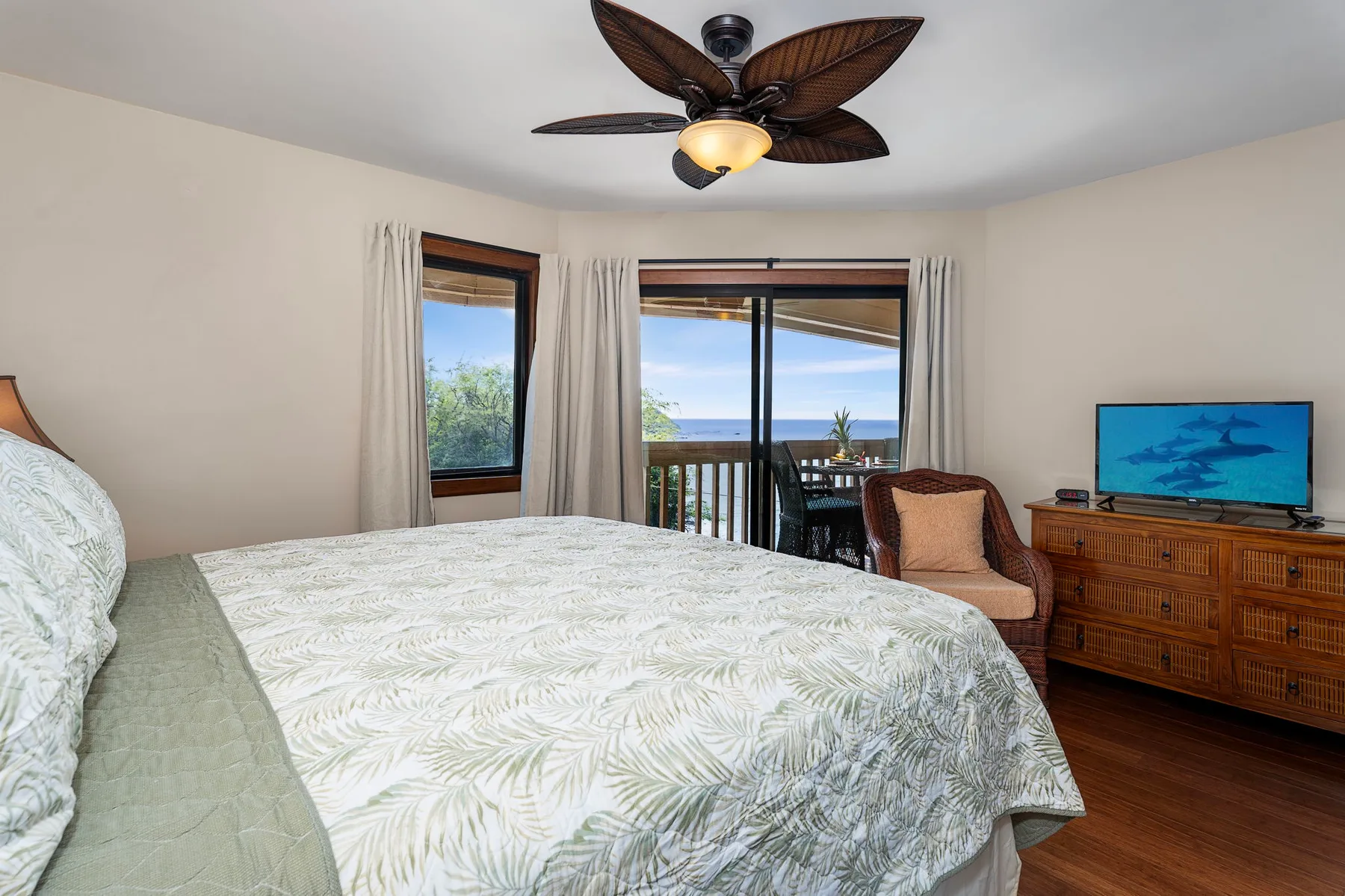 A bedroom with a large bed, a television, and sliding glass doors opening to a balcony.