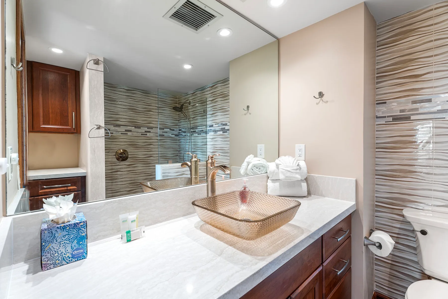 A bathroom vanity with a basin sits beside a tiled shower area.