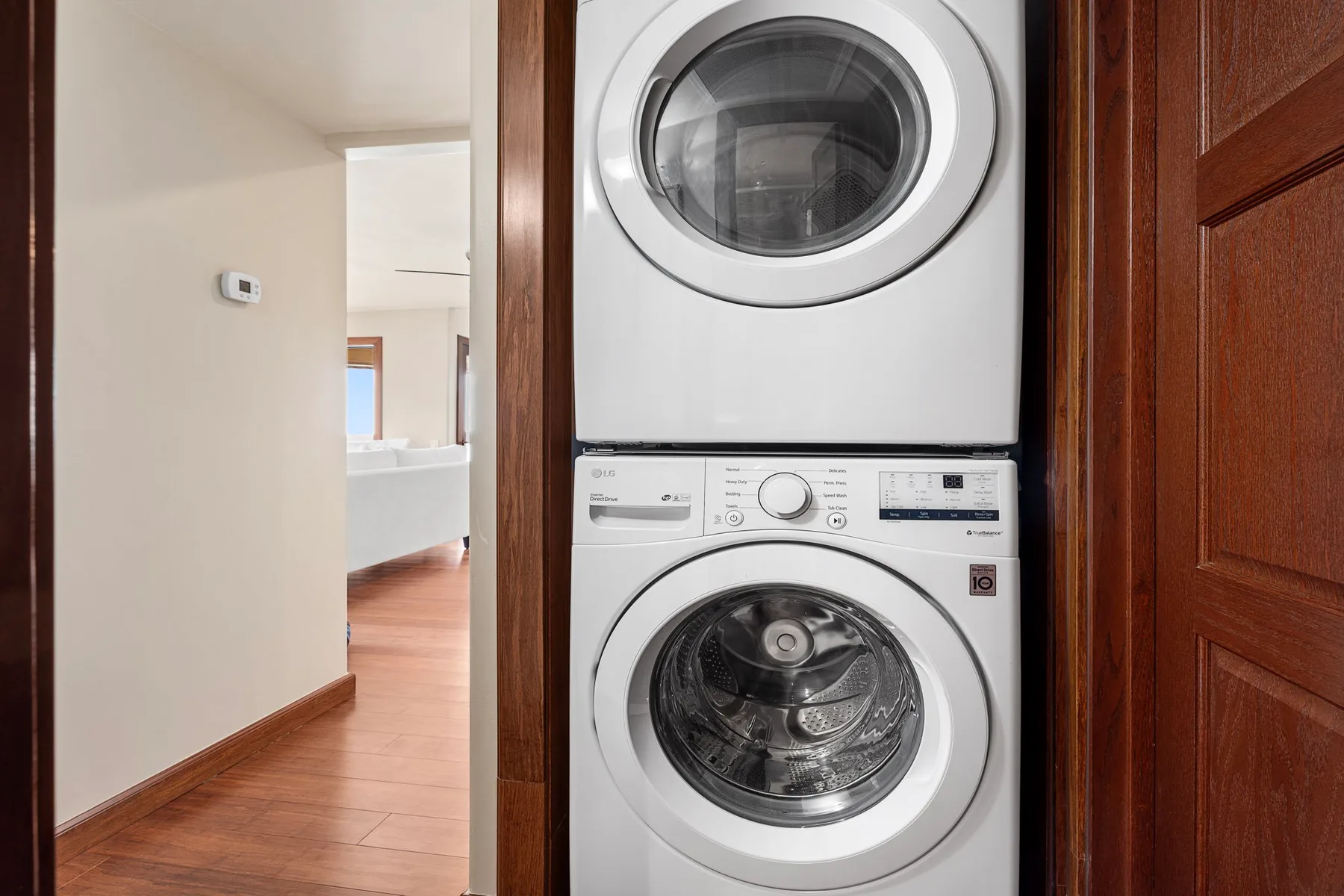 A laundry area with a stacked washer and dryer beside a hallway.
