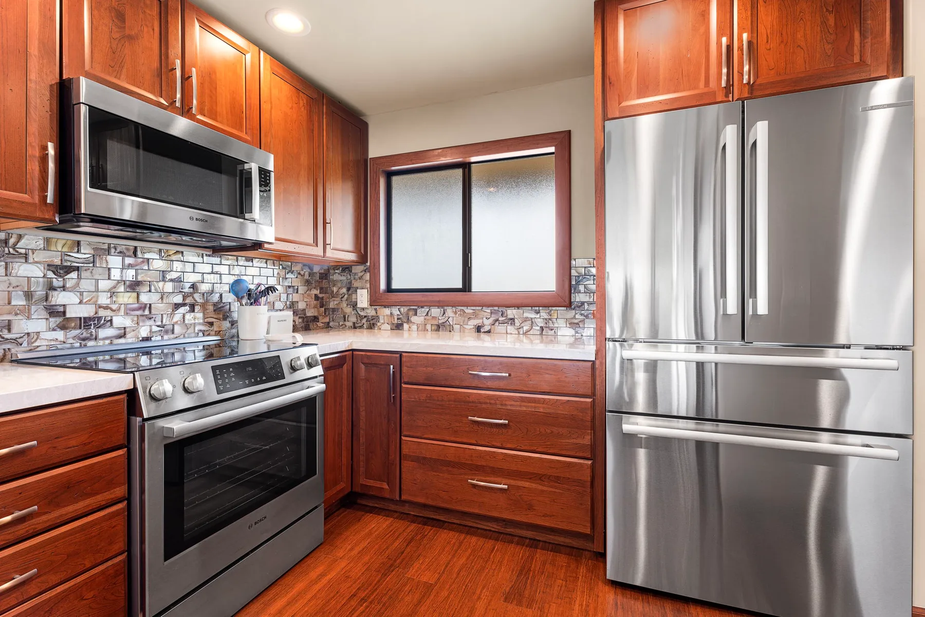 A kitchen with wooden cabinets, stainless steel appliances, and a tiled backsplash.
