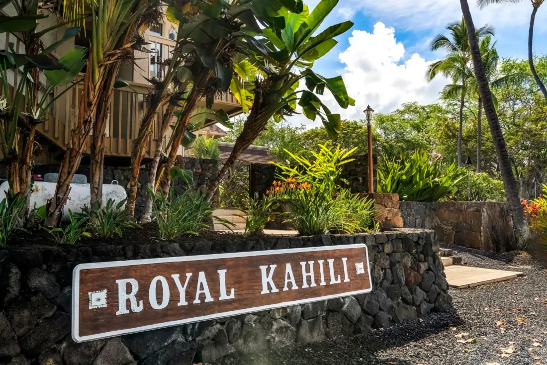 A landscaped tropical property entrance features a prominent Royal Kahili sign.