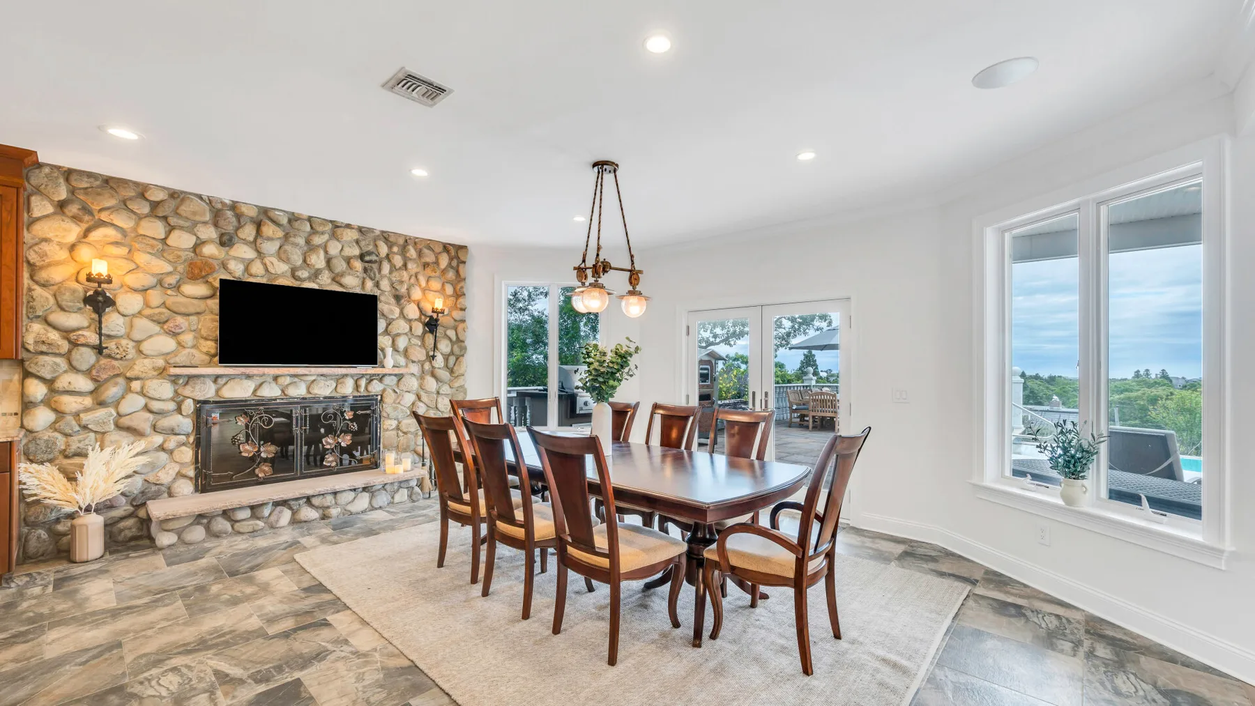 A dining room with a wooden table and stone fireplace.