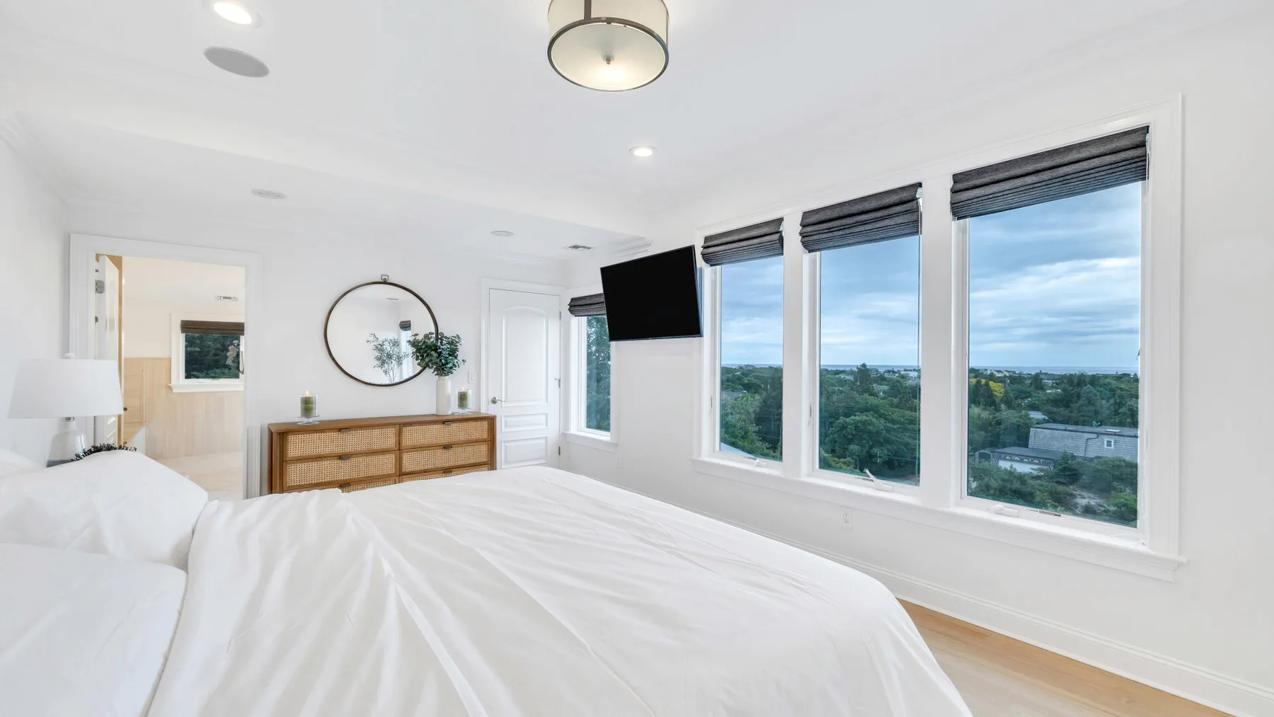 A bright bedroom with a large bed and windows overlooking greenery.