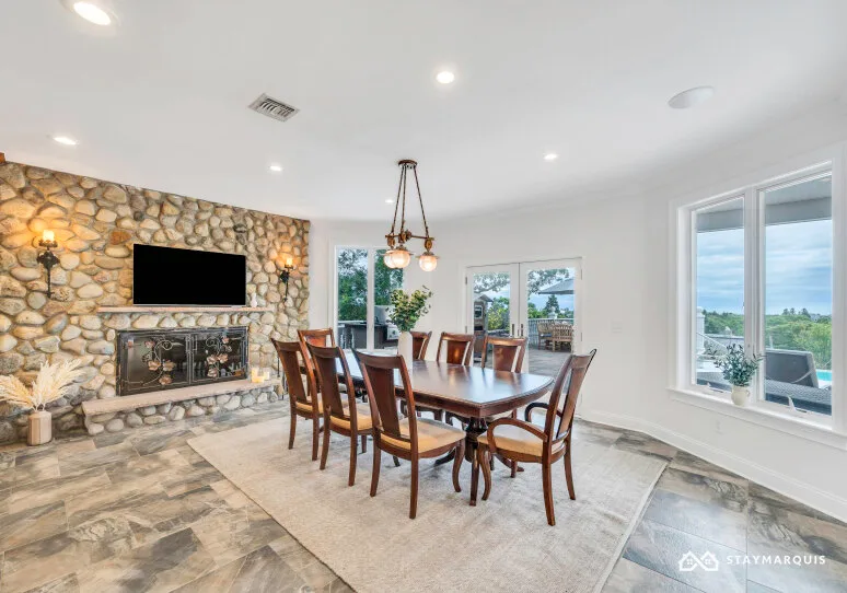 A dining area with a wooden table and stone fireplace.