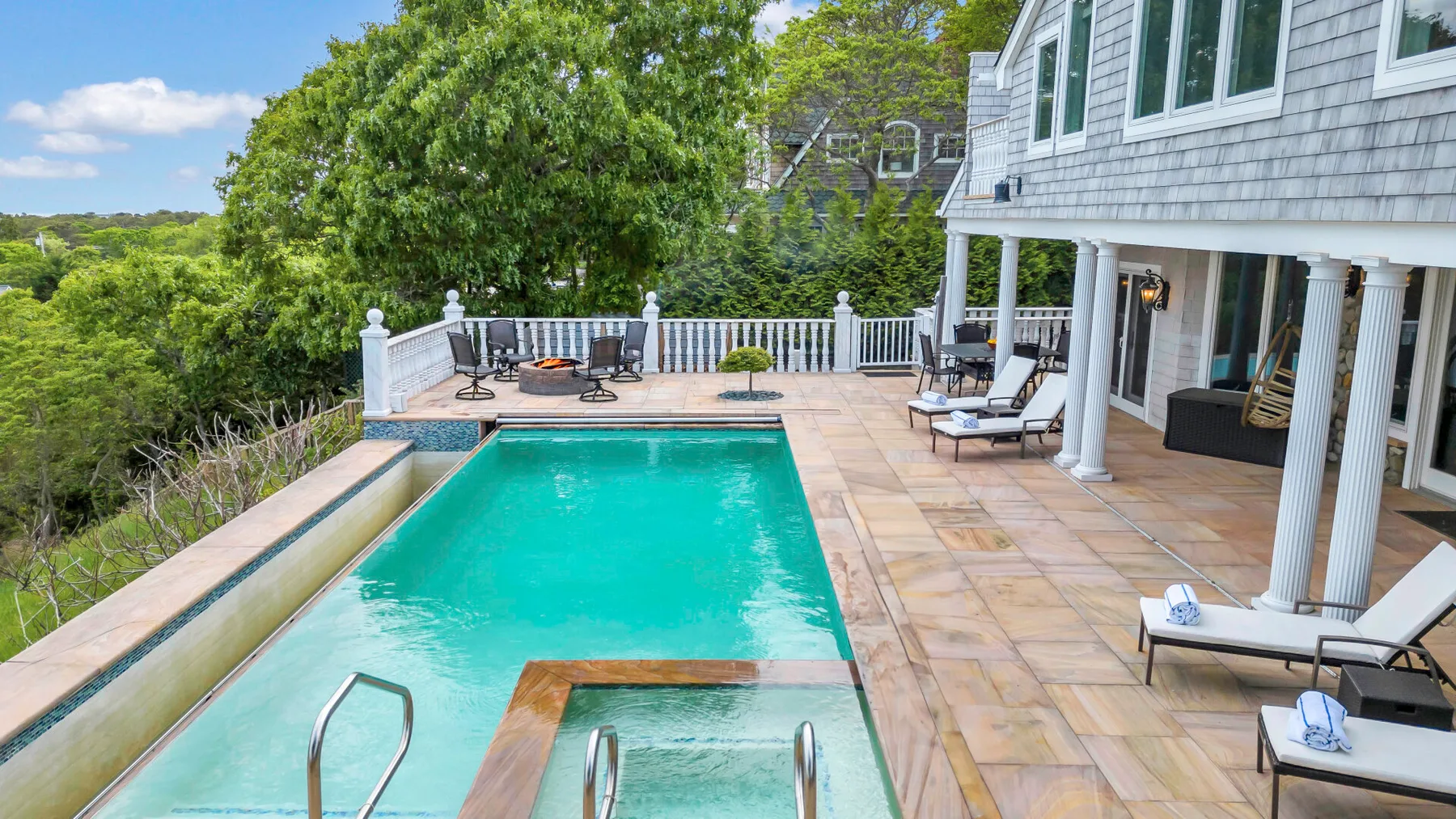 An outdoor swimming pool and surrounding patio beside a house.