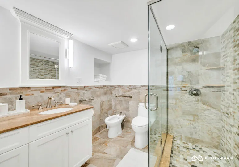 A bright bathroom with a long vanity and a glass-enclosed shower.