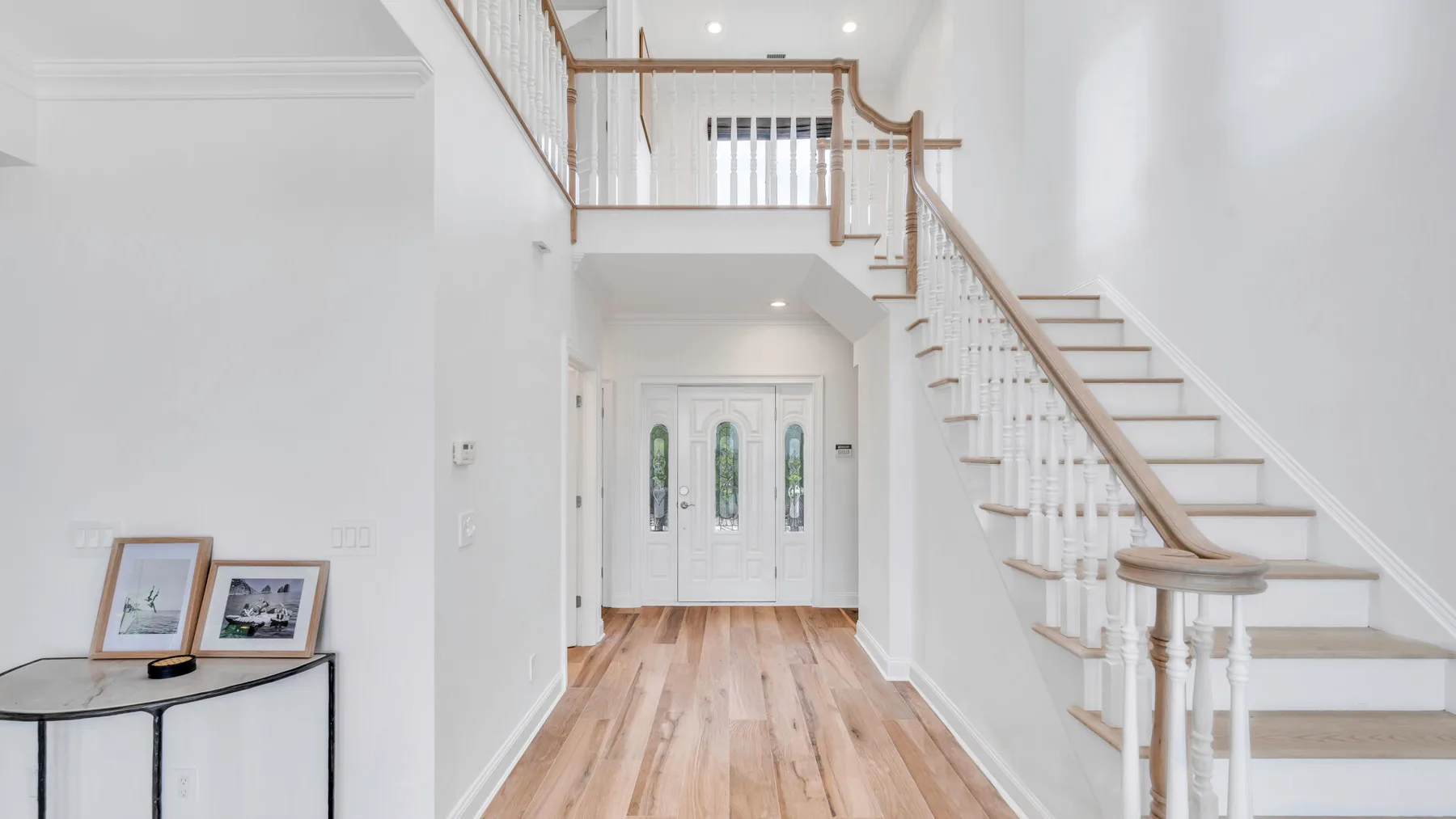 A bright entry hall with a staircase and wood flooring.