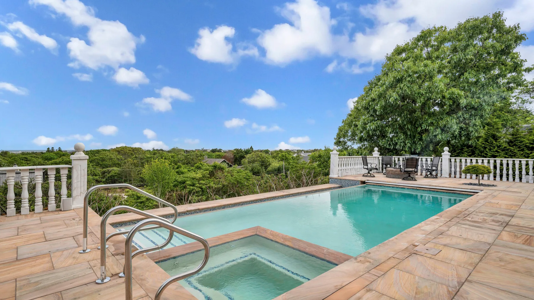 An outdoor swimming pool with a small adjoining shallow section and paved deck.