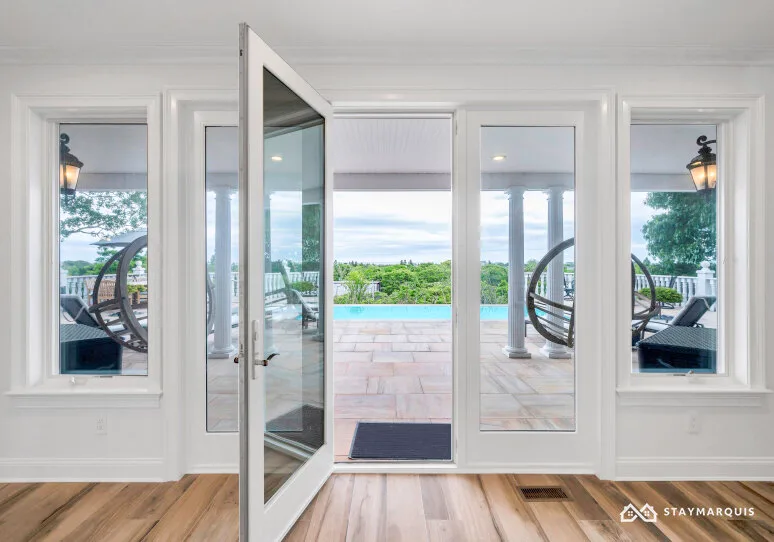 A bright interior opens through a glass door onto a patio and swimming pool.