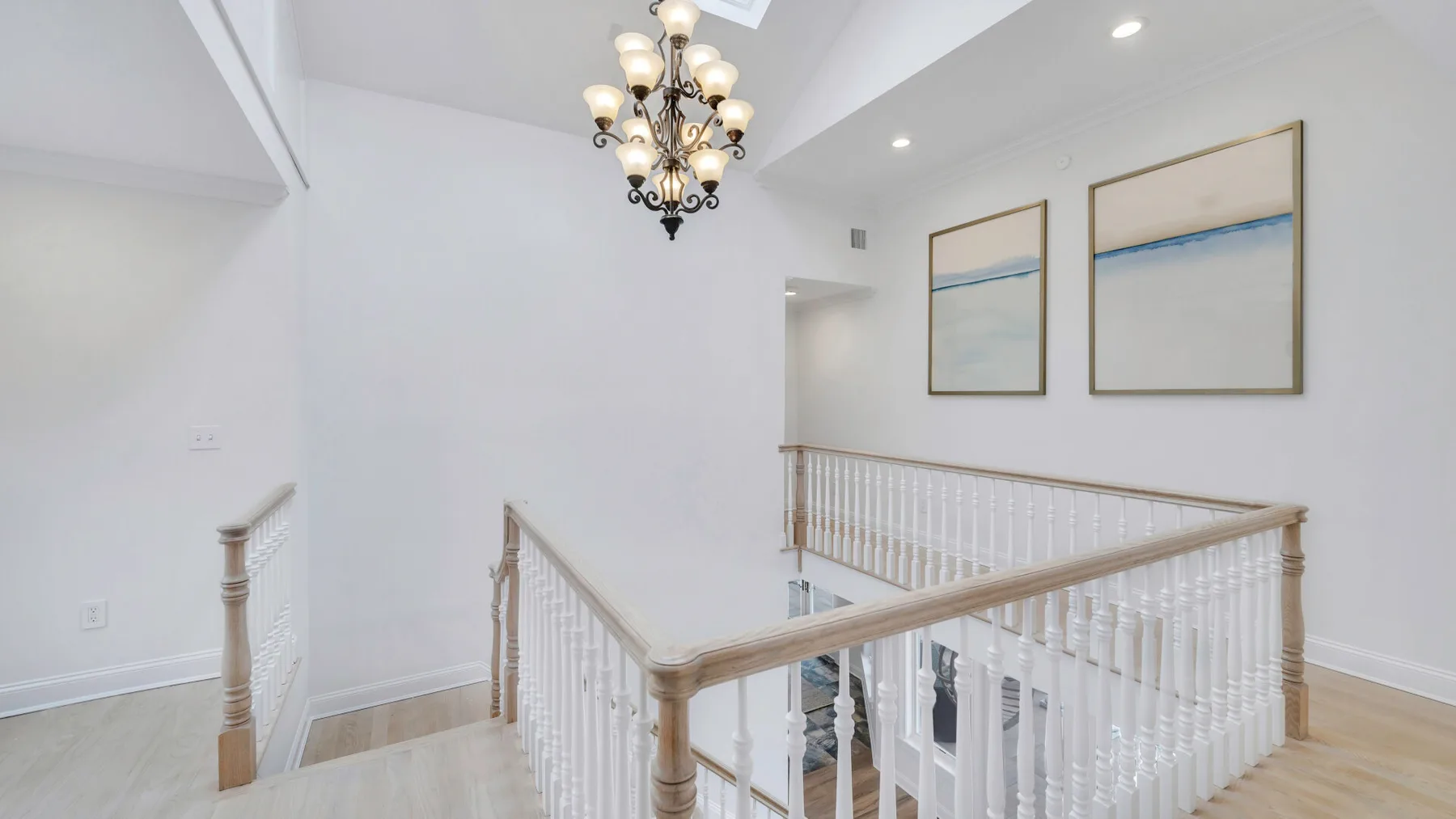 An upstairs landing with white railings and framed artwork.