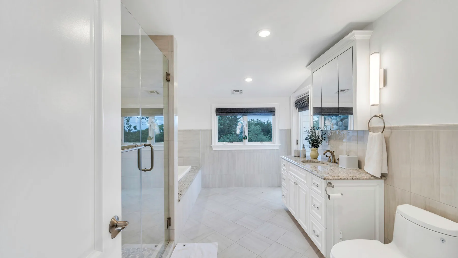 A bright bathroom with a glass shower and a long vanity.