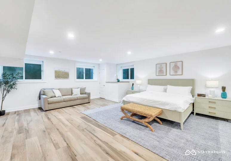 A bright bedroom with a large bed, a seating area, and a rug.
