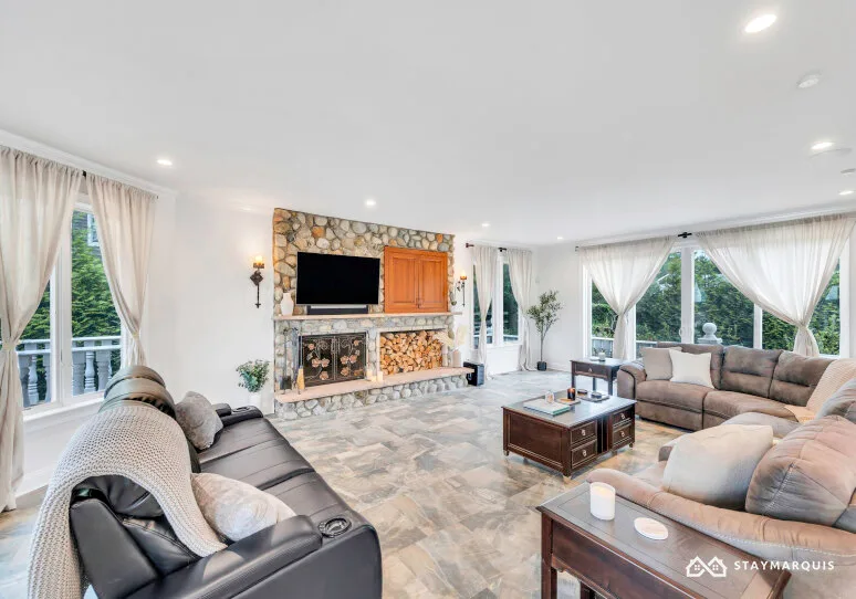 A bright living room with seating arranged around a stone fireplace and coffee table.