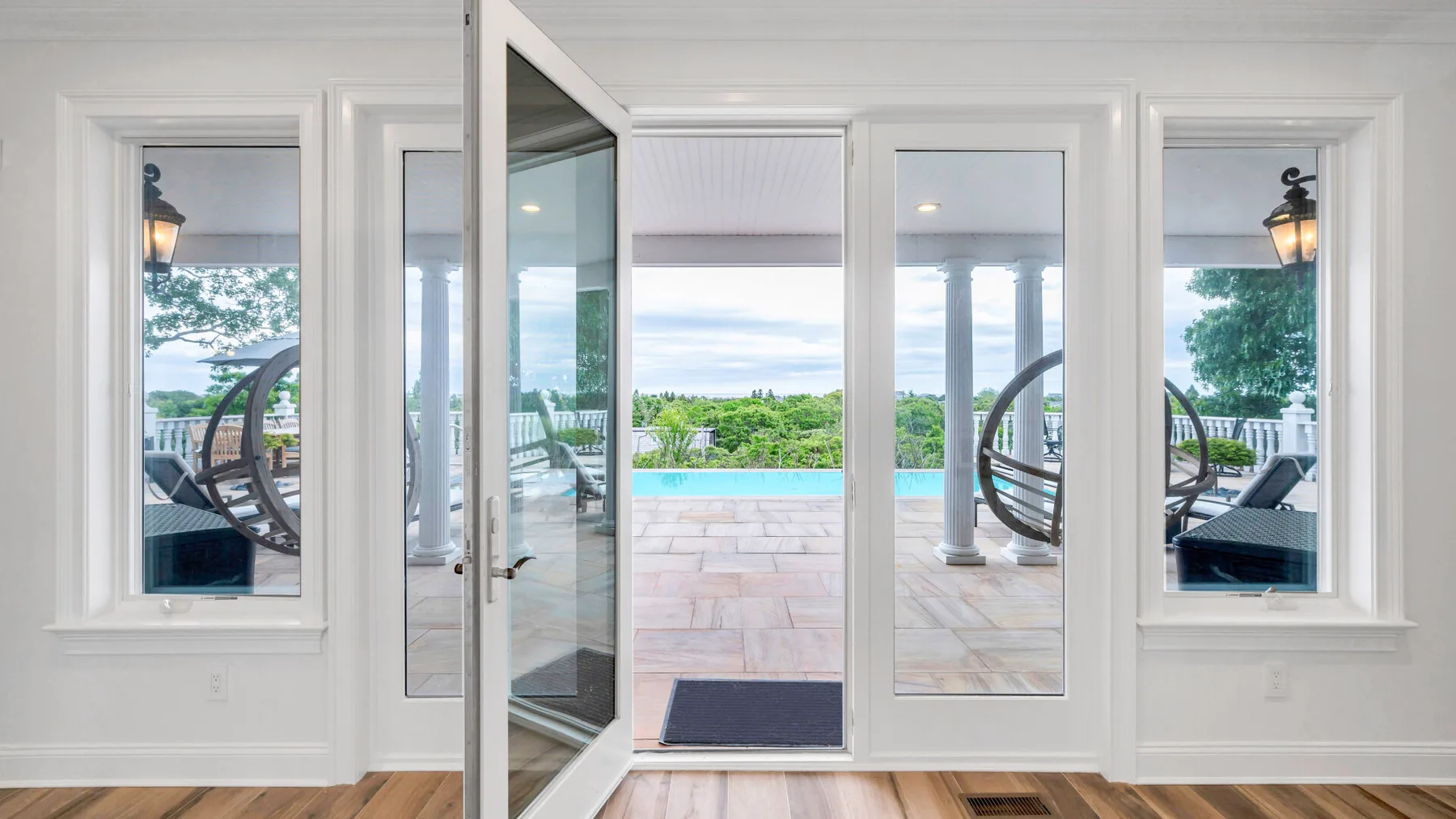A bright room opens through glass doors onto a patio with a swimming pool.