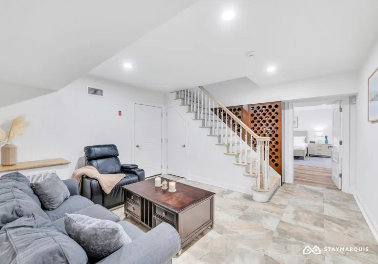 A living room with seating and a coffee table beneath a staircase.