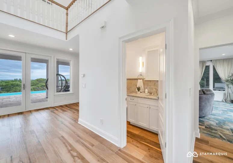 A bright interior hallway opens onto a kitchen and living area, with glass doors overlooking a pool.