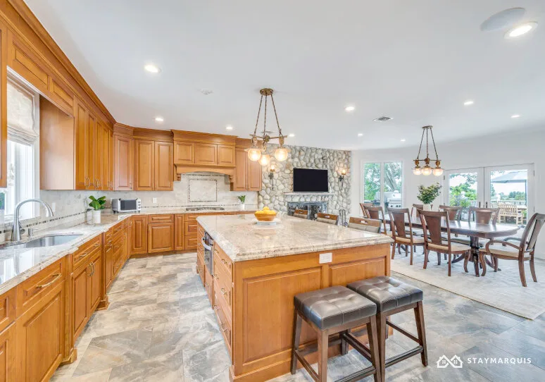 A spacious kitchen with wooden cabinetry, a central island, and a dining area.