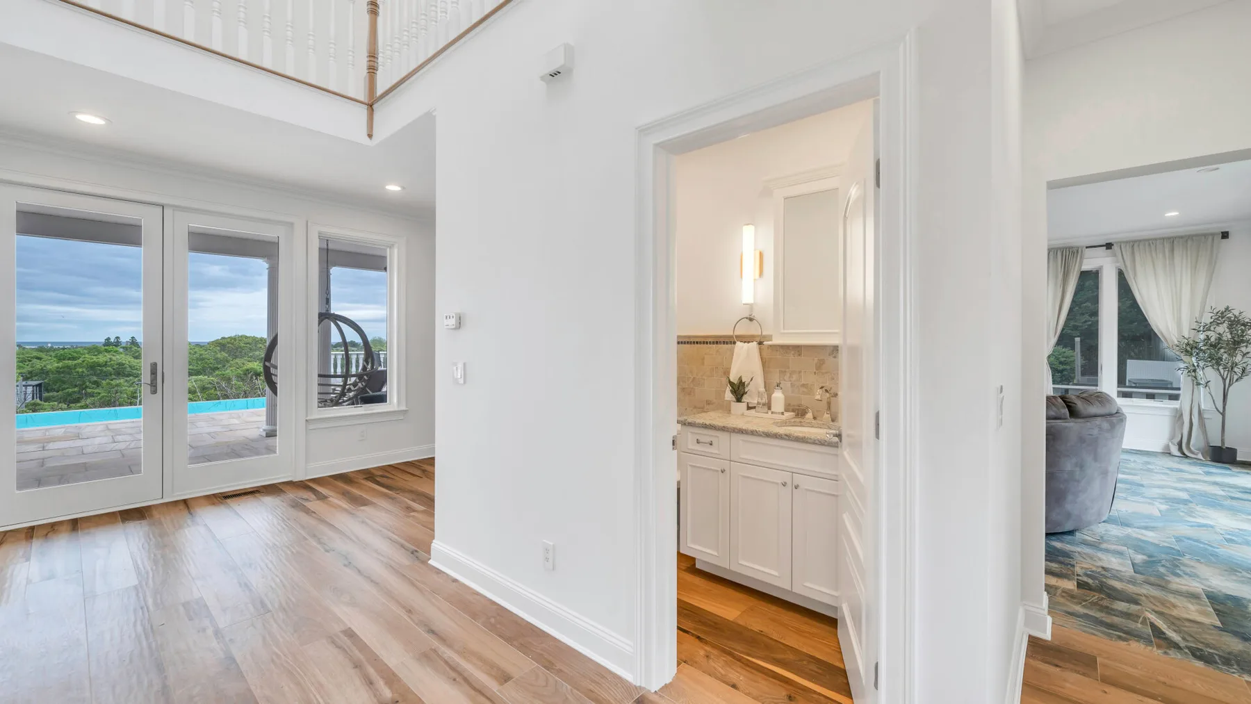 A bright interior hallway opens onto a bathroom and a room with seating.