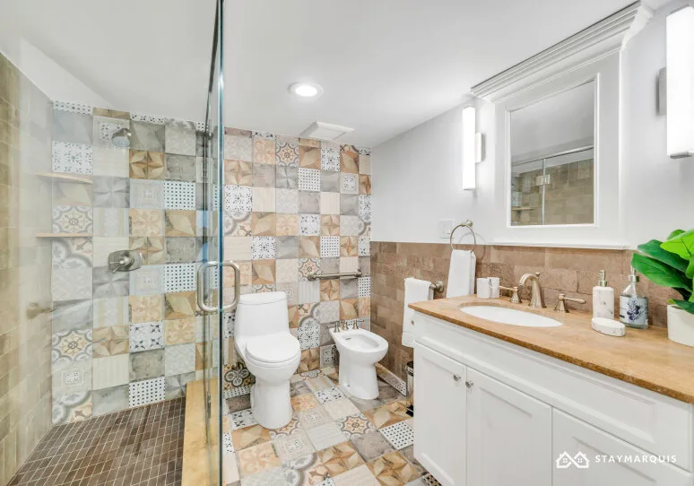 A bathroom with a glass shower, toilet, and white vanity.