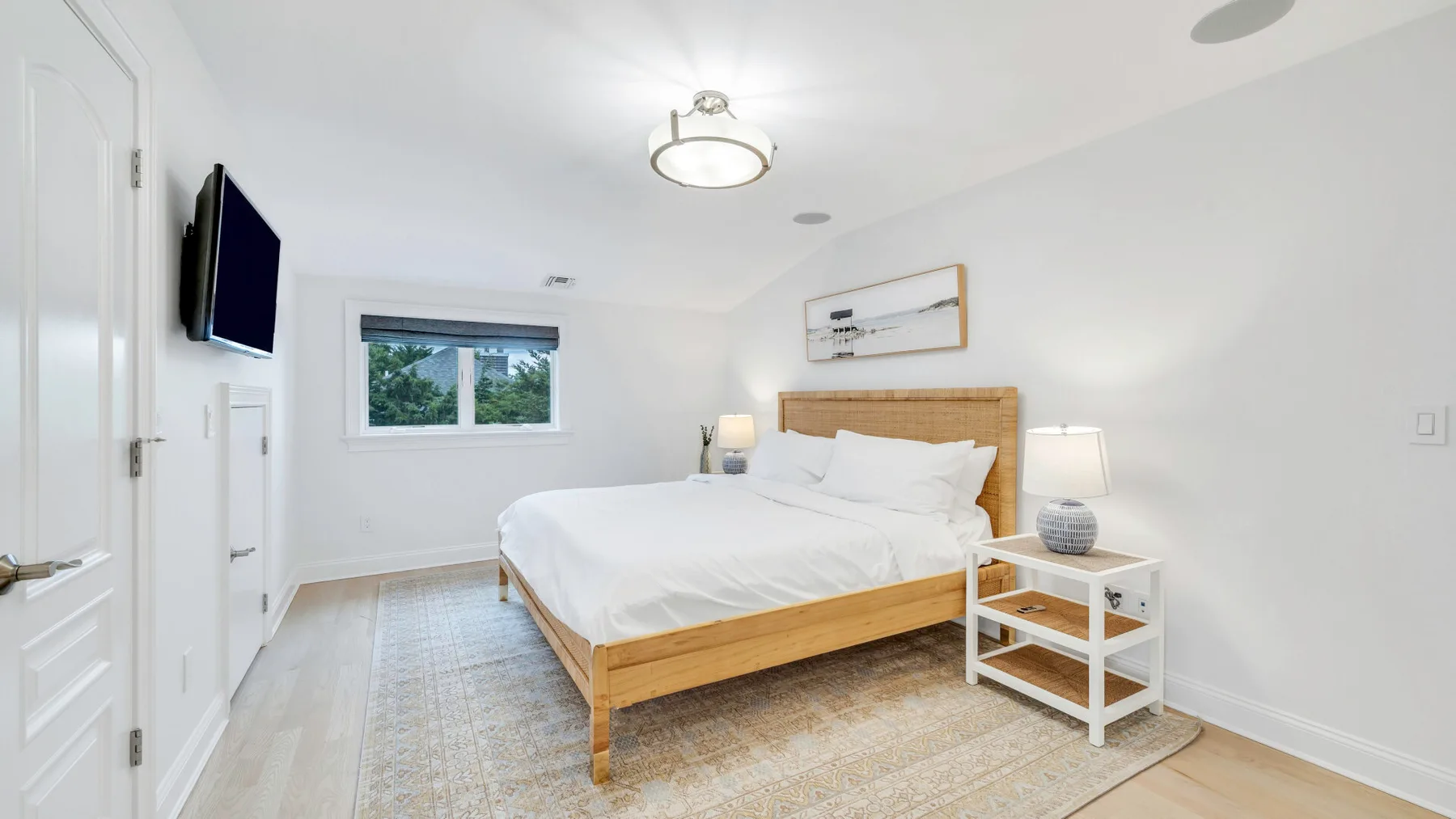 A bright bedroom with a wooden bed and white bedding.