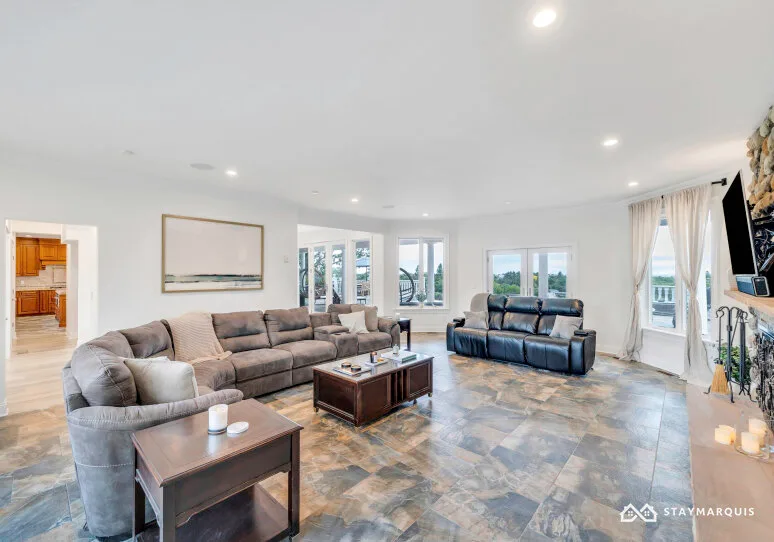 A bright living room with seating, a coffee table, and large windows.
