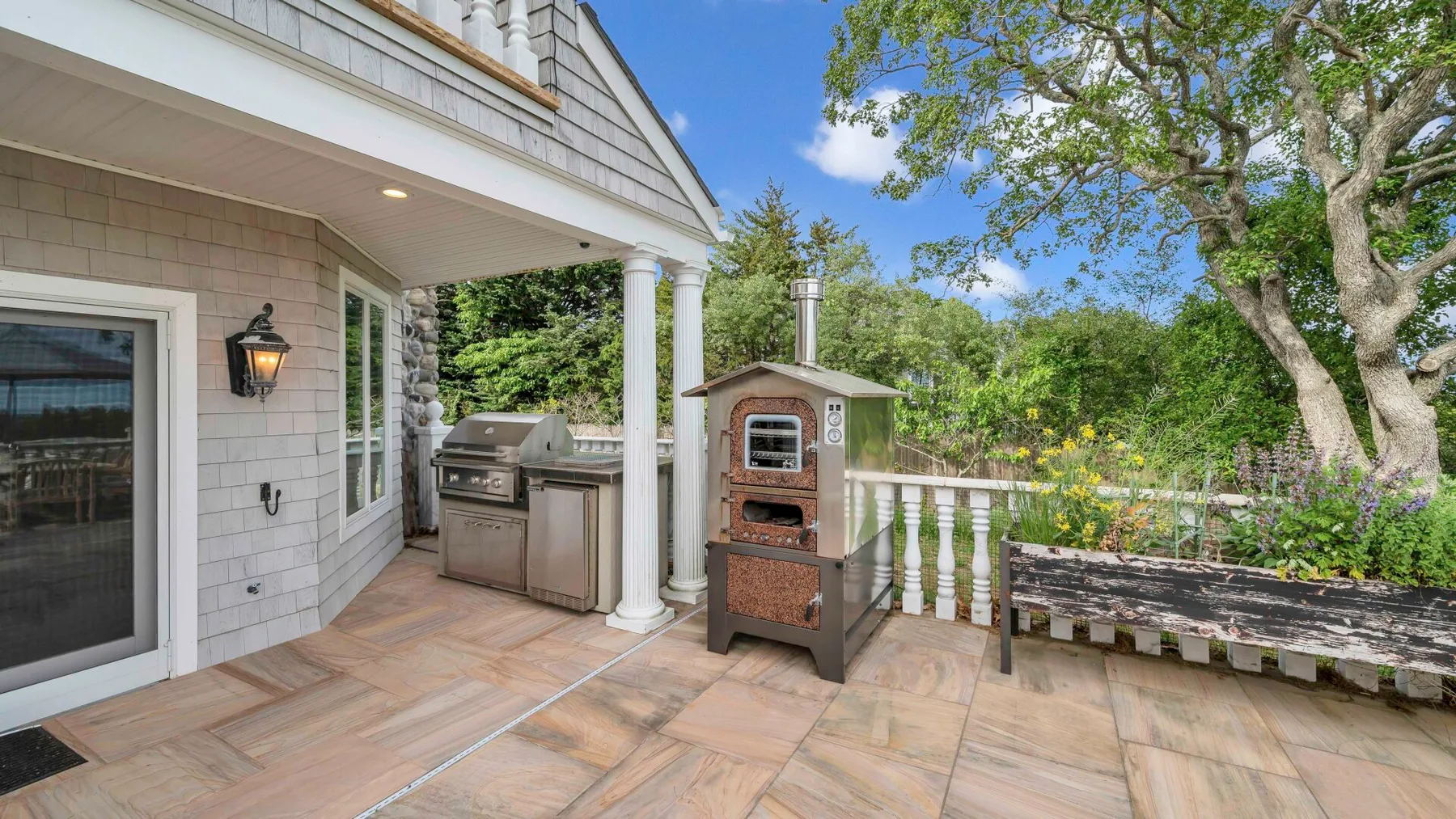 An outdoor patio with a covered cooking area and a wood-fired oven.
