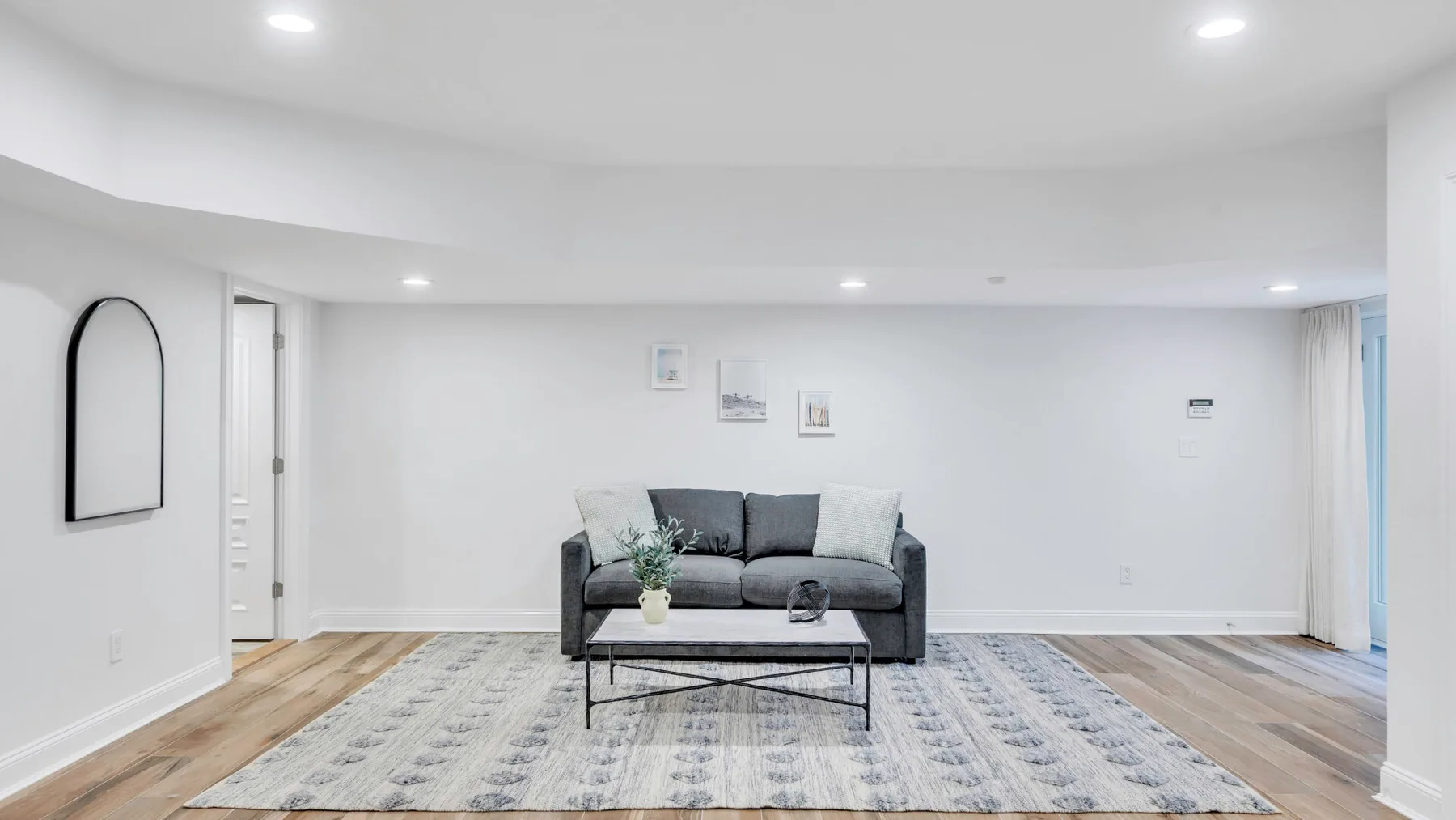A bright living room with a gray sofa and a patterned rug.