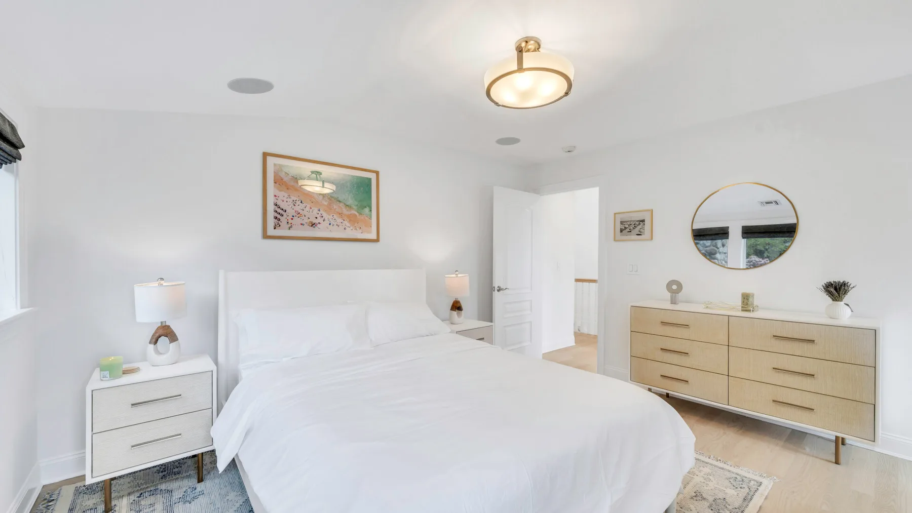 A bright bedroom with a neatly made bed and a wooden dresser.