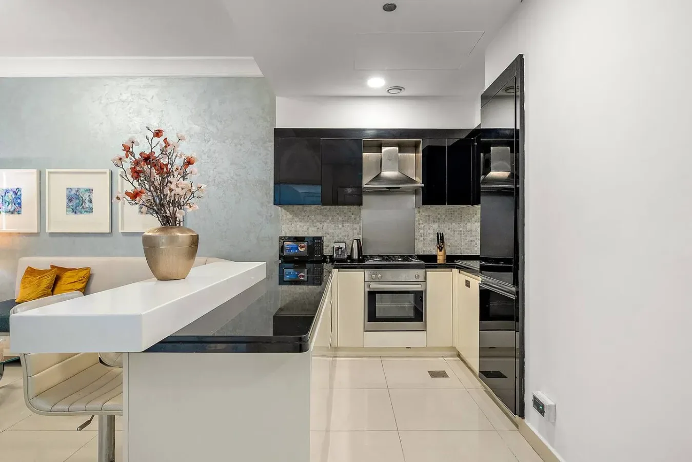 A modern kitchen with dark cabinets, light countertops, and a small dining counter.